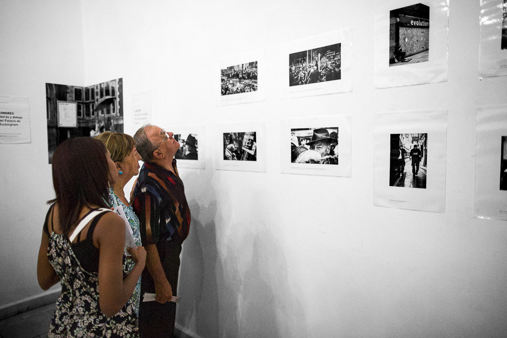 Image of gallery attendants at "Londres. Detrás y debajo del Palacio de Buckingam" exhibition space. Arte Soy Gallery in Santiago de Cuba, Cuba.. This is an image related to a project inside Pedro Rodrigues (Treze413) graphic design portfolio.