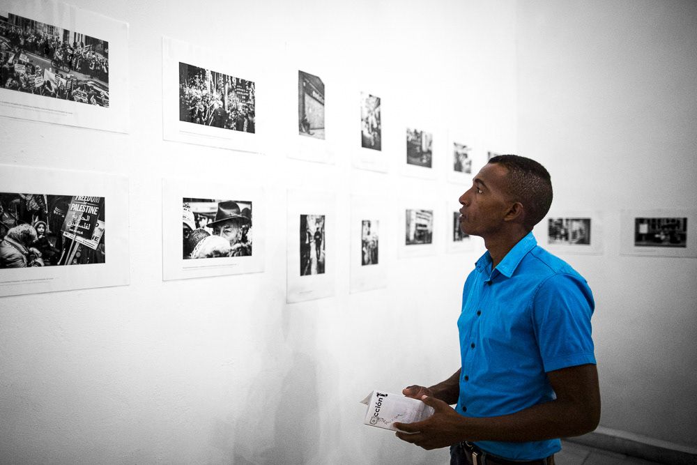 Image of gallery attendants at "Londres. Detrás y debajo del Palacio de Buckingam" exhibition space. Arte Soy Gallery in Santiago de Cuba, Cuba.. This is an image related to a project inside Pedro Rodrigues (Treze413) graphic design portfolio.